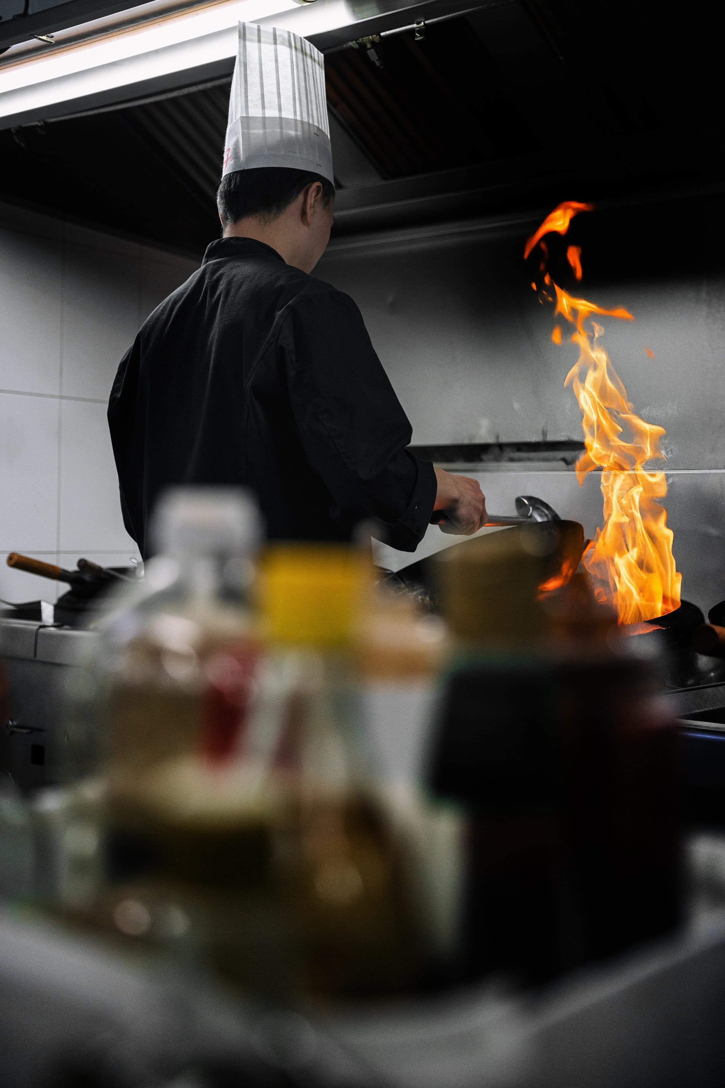 Chef a cozinhar sobre a chama do wok